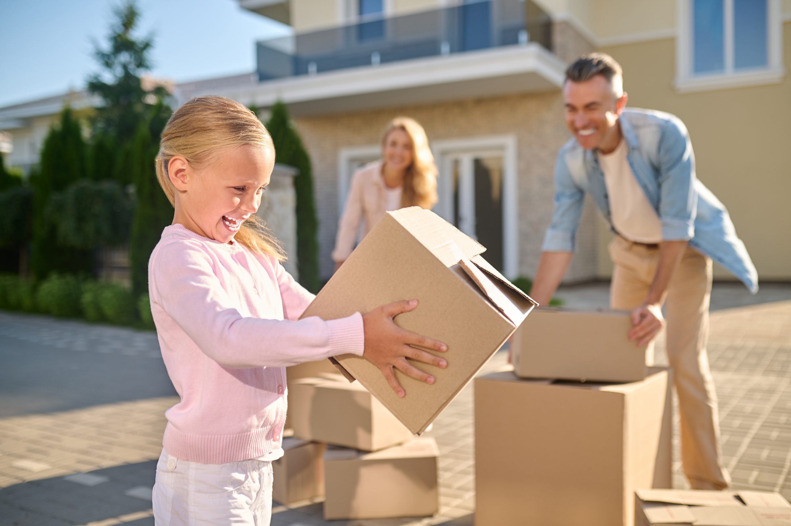 Cute family unpacking cardboard boxes while moving to a new house